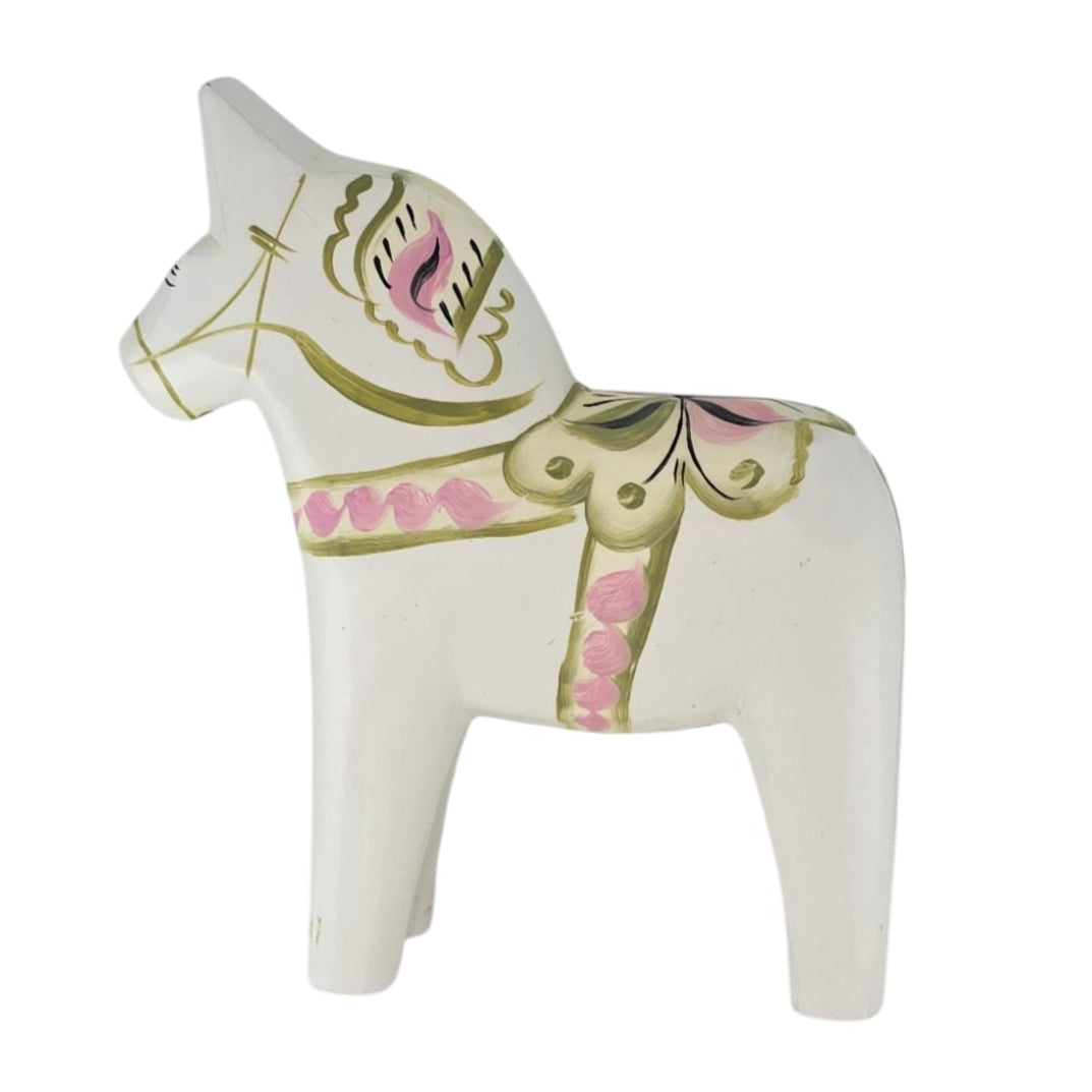 A white ceramic figurine, named Dala Horse: Pastel on White Swedish Dala Horse with Kurbits, is hand-painted with green and pink patterns akin to a Swedish Dala Horse, set against a plain background.