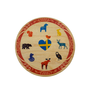The Birch Swedish Animals Coaster from a Swedish Gift Store is a charming round wooden plaque, adorned with a heart-shaped Swedish flag and vibrant illustrations of animals like a moose, owl, and fox, bordered with red patterns.