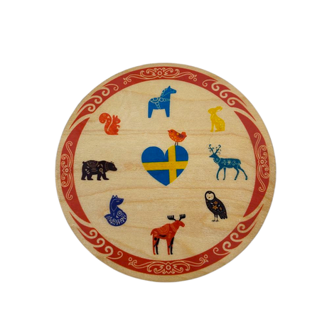The Birch Swedish Animals Coaster from a Swedish Gift Store is a charming round wooden plaque, adorned with a heart-shaped Swedish flag and vibrant illustrations of animals like a moose, owl, and fox, bordered with red patterns.