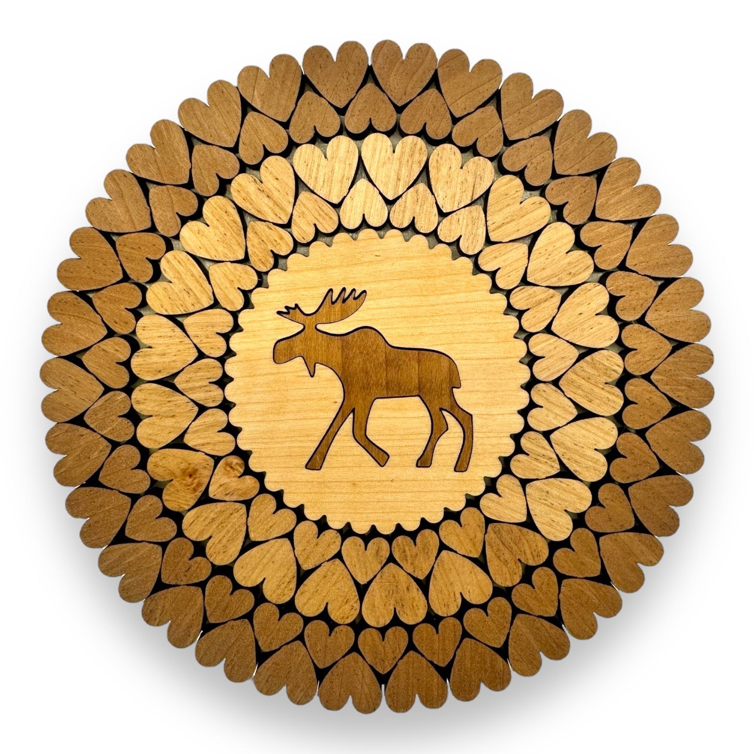 The Trivet: Moose Trivet with Laser Cut Hearts (6) is an exquisite circular wooden trivet featuring a moose silhouette surrounded by heart patterns in shades of brown. Handmade in Estonia, it beautifully combines artistry and functionality.