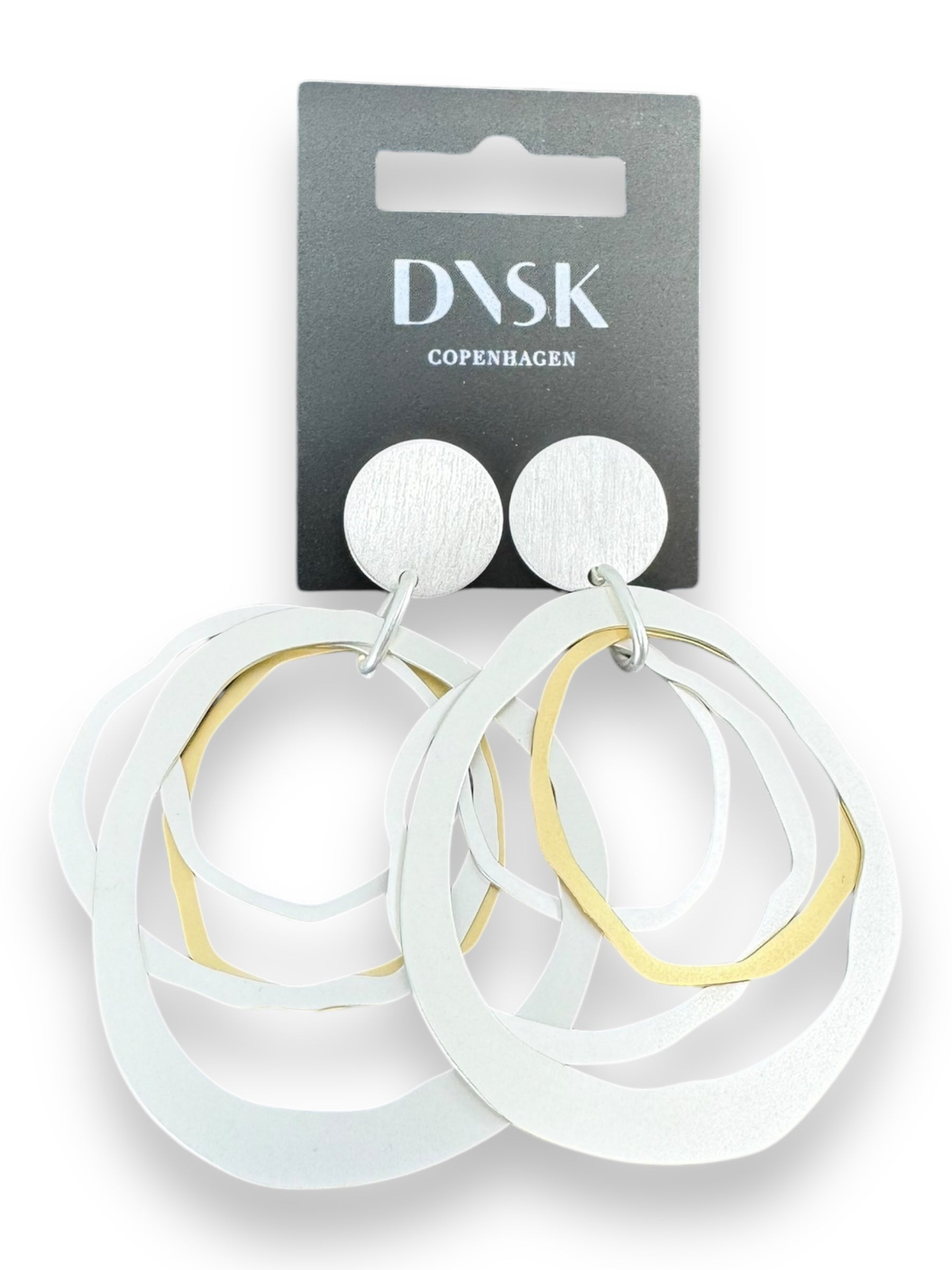 The Alaya Two Tone Elysian earrings feature multiple interlocking circles in silver and gold tones, highlighting a minimalist Nordic design. These versatile jewelry pieces, crafted from high-quality brass to complement any style, are elegantly displayed on a black card labeled DASK Copenhagen.