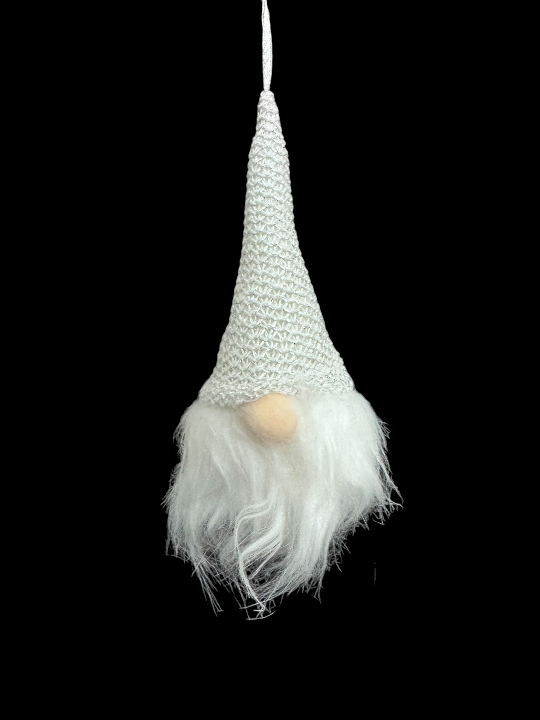 The Light Up Tomte Gnome, featuring a white knitted hat, fluffy white beard, and round nose, hangs elegantly against a black background. Battery operated with A76 (LR44) included, it adds charm to your space.