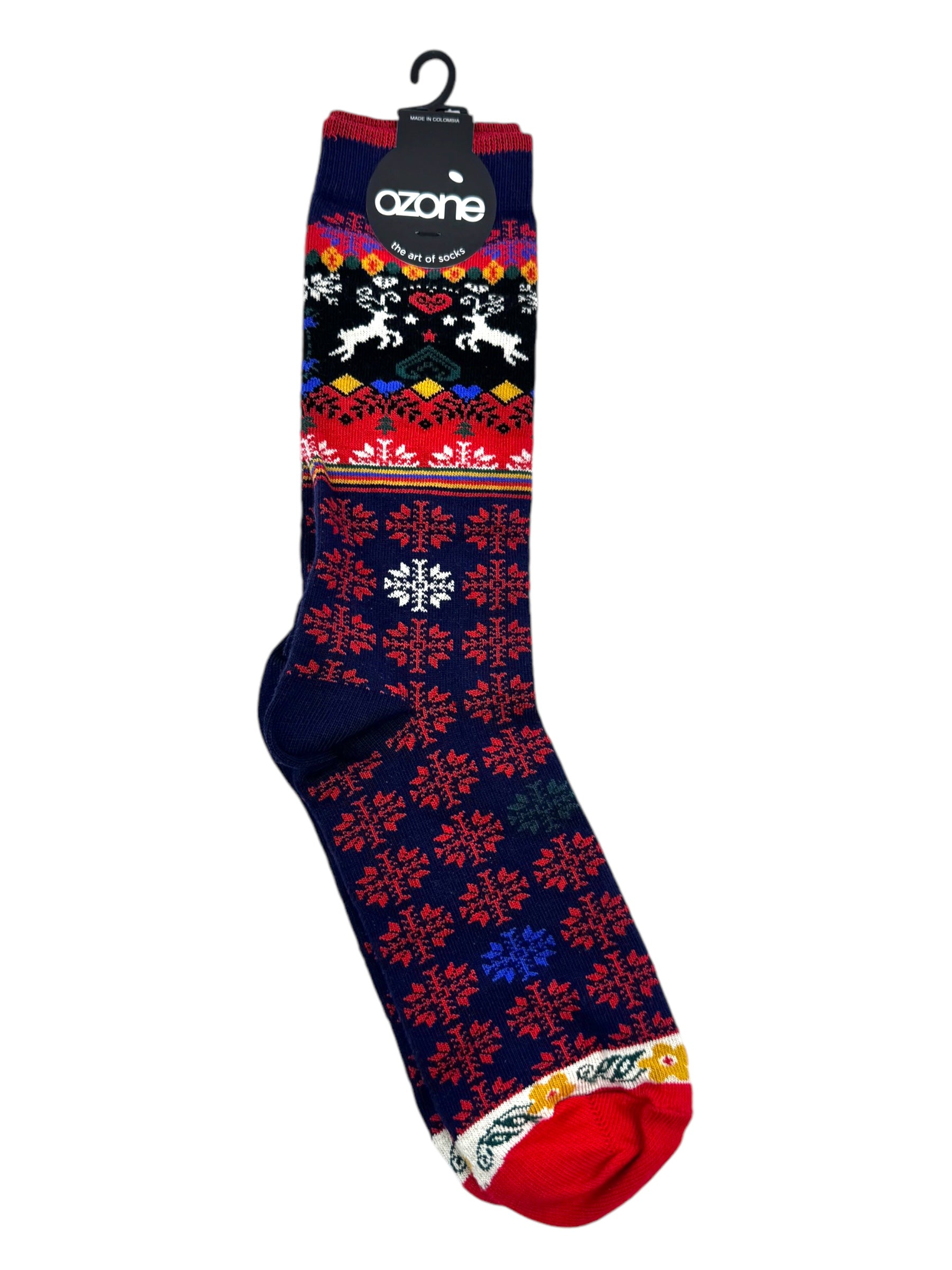 The Ozone - Renne socks are vibrant women's novelty crew socks showcasing Scandinavian holiday designs of reindeer and snowflakes set against a black backdrop, accented with red, blue, and white. Crafted from high-quality natural cotton fiber, they hang elegantly on a hook.