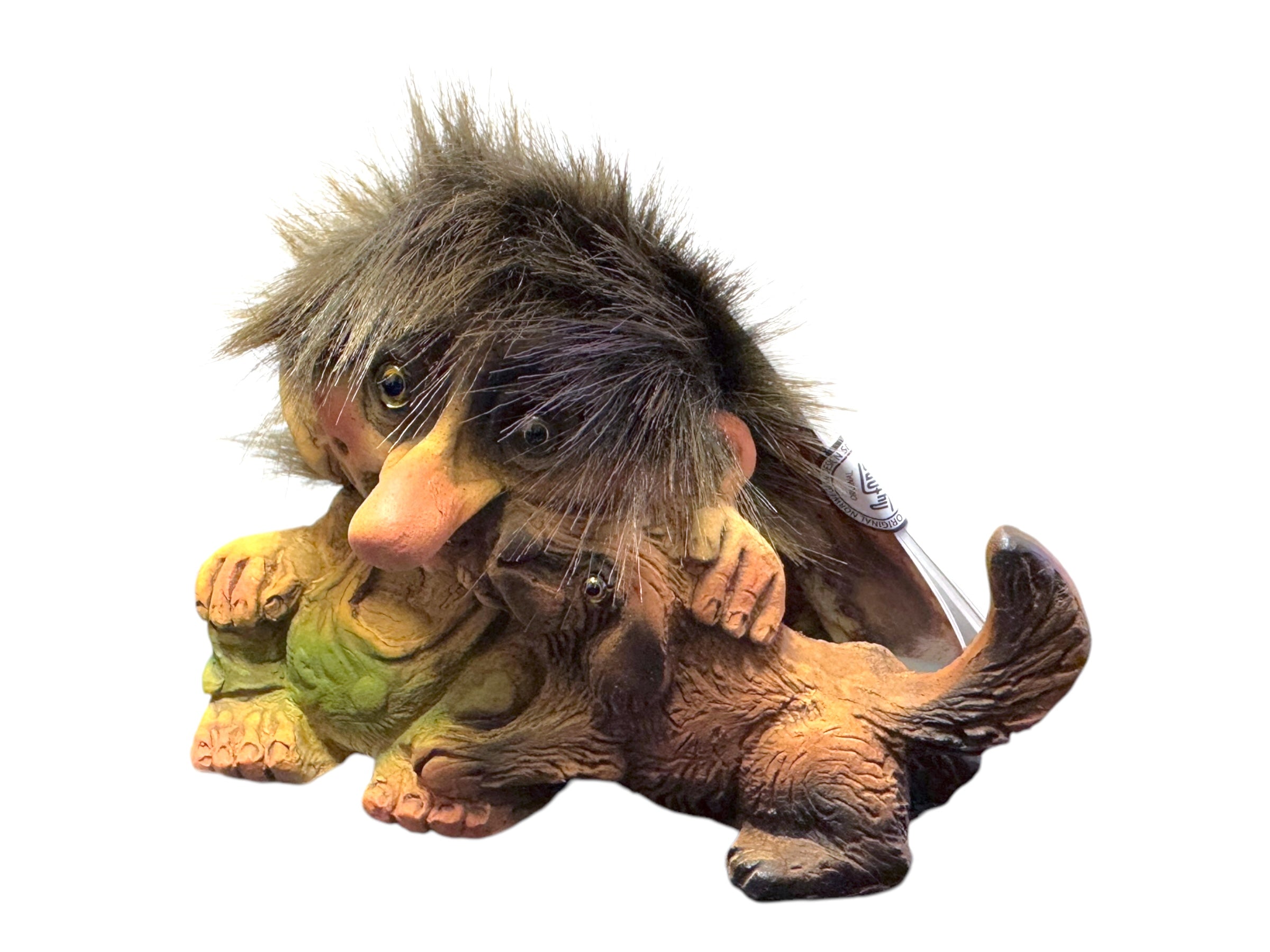 The "Troll: NyForm - Troll with Dog" figurine features a whimsical troll with messy hair tenderly embracing a small, furry dog, highlighting the enchanting charm of handmade Norwegian design. This international collector's item beautifully combines whimsy and craftsmanship.