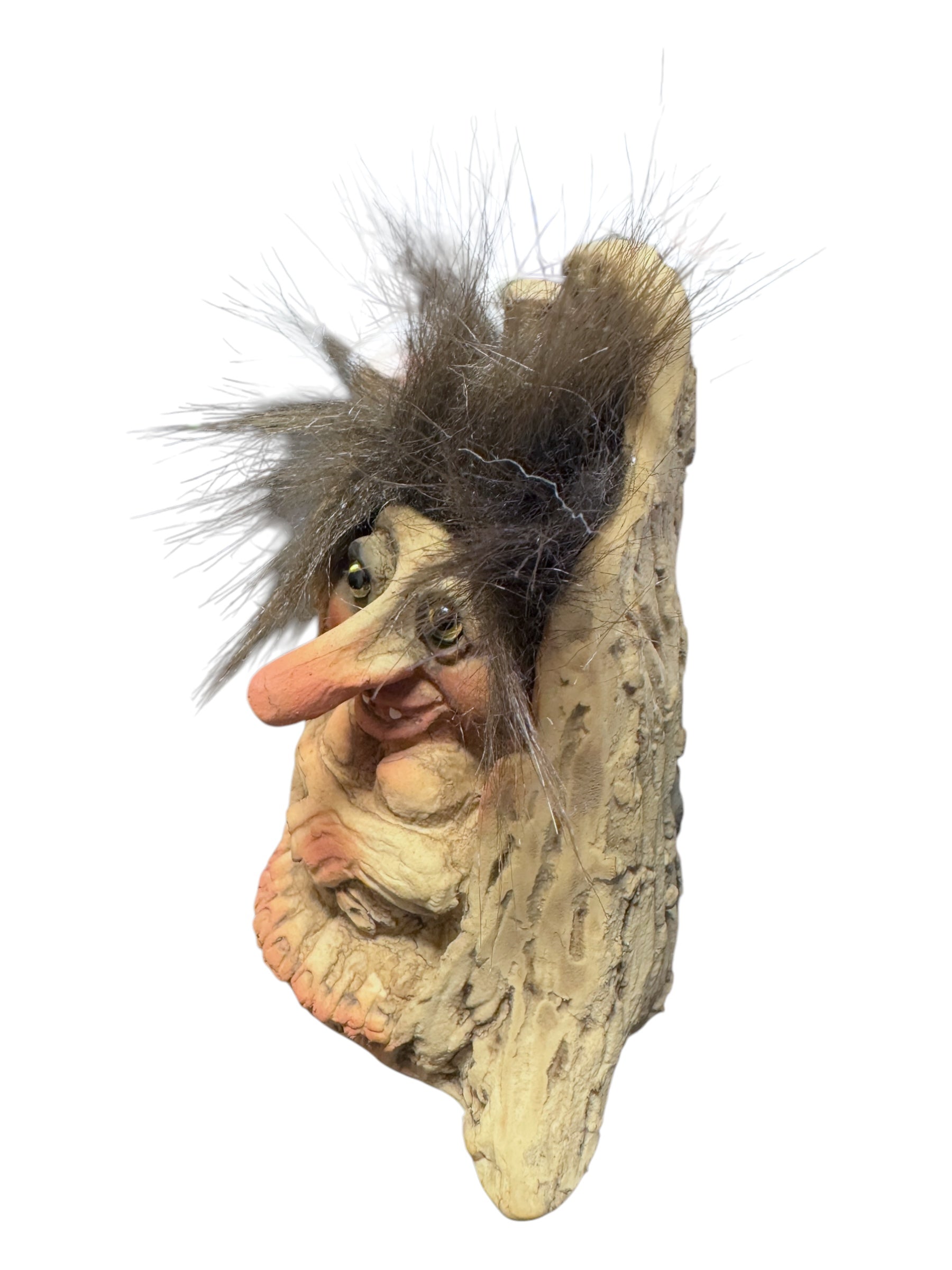 The Troll: NyForm - Troll in Stump figurine, featuring a long nose, shaggy hair, and large eyes, rests against a textured, bark-like surface. This handmade Norwegian design is ideal for collectors seeking unique items.