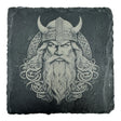 Engraved image of a Viking warrior with horned helmet and beard on a square slate coaster. The design, from the Coaster: Warrior, Viking Head - Celtic Viking Symbol Slate Coaster, is inspired by Norse mythology and Celtic Viking symbols.