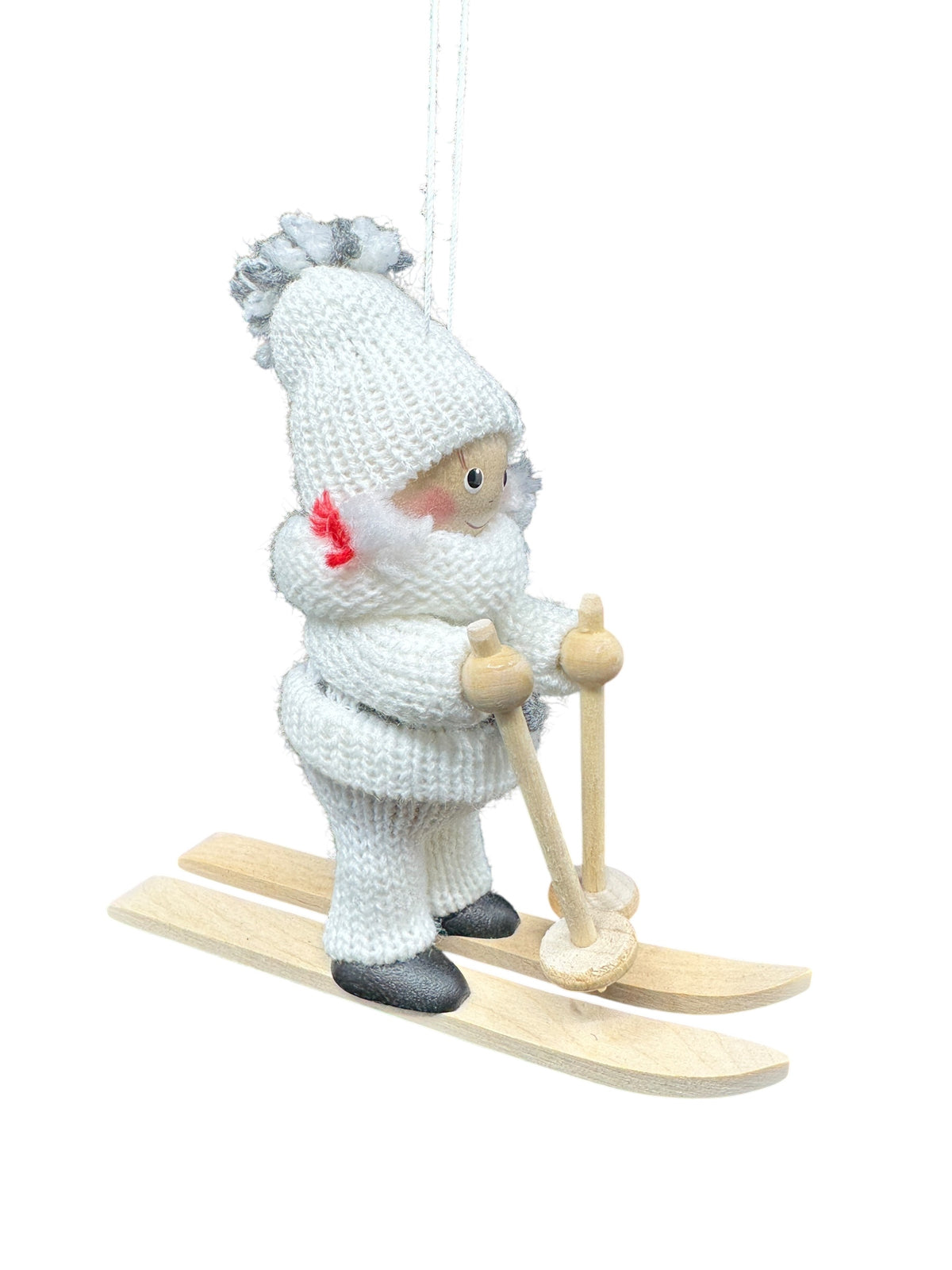 The Figurine: Scandinavian Girl on Skis with White Snow Suit features a girl in a white knitted outfit and hat, holding poles and standing on wooden skis, suspended by a string.