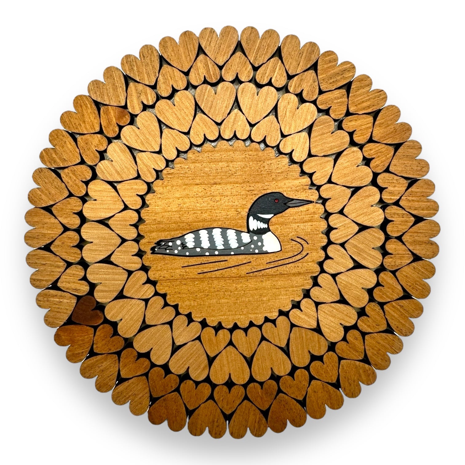 The Loon Trivet with Laser Cut Hearts (6) is a beautifully crafted wooden trivet with laser-cut heart segments surrounding an image of a pristine loon at the center.