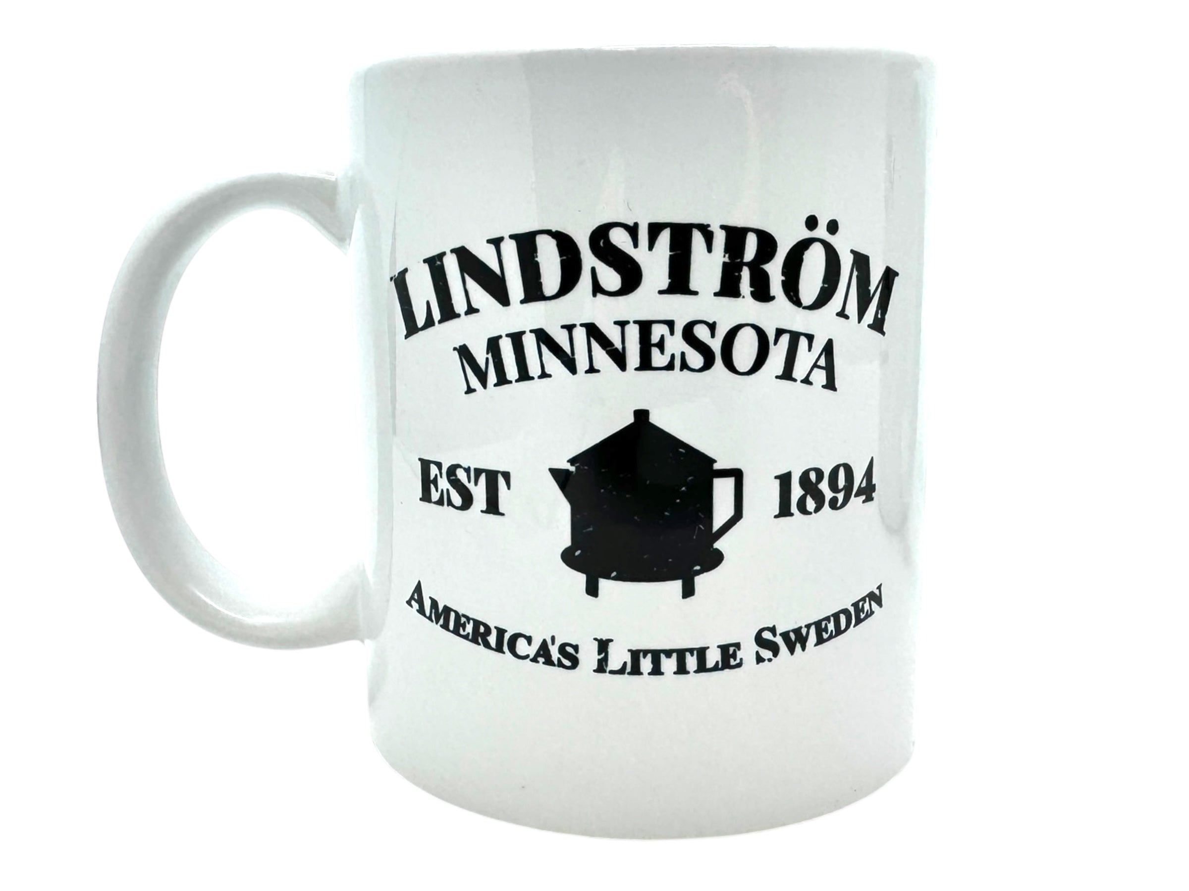 Discover the Mug: Lindstrom EST 1894, a ceramic mug adorned with "Lindström, Minnesota" text, established in 1894, and the phrase "America's Little Sweden" alongside a teapot silhouette. A delightful gem from the Swedish Gift Store.