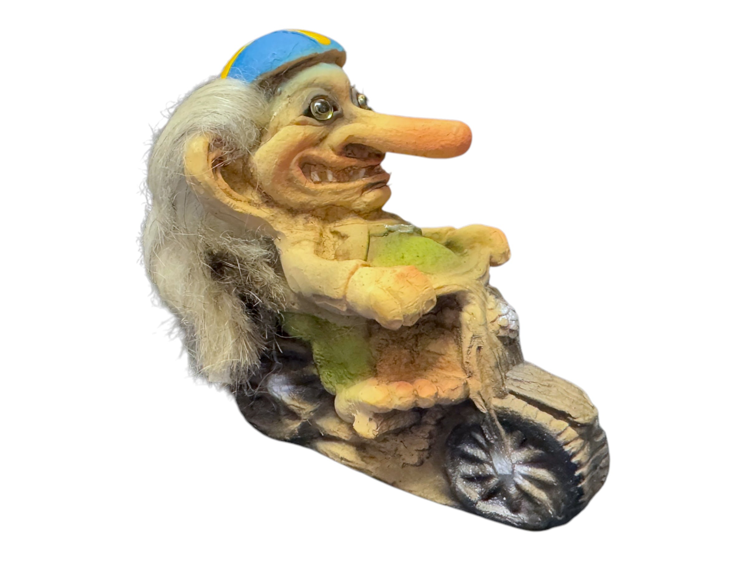 The Troll: NyForm - Troll on Motorcycle is a whimsical collector's item, featuring a troll figurine with long hair and a blue cap riding a small wooden motorcycle. This Norwegian design captures charm and fantasy in every delightful detail.