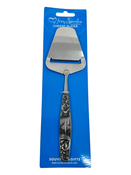 The Cheese Slicer: Sweden Metal Cheese Slicer features an ornate handle and comes in blue packaging, showcasing Swedish-designed elegance and Nordic heritage.