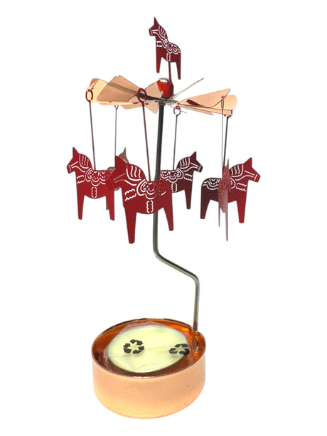 A rose-gold candle holder and spinner by Pluto Design, featuring red Dala horse ornaments suspended above a tea light base.