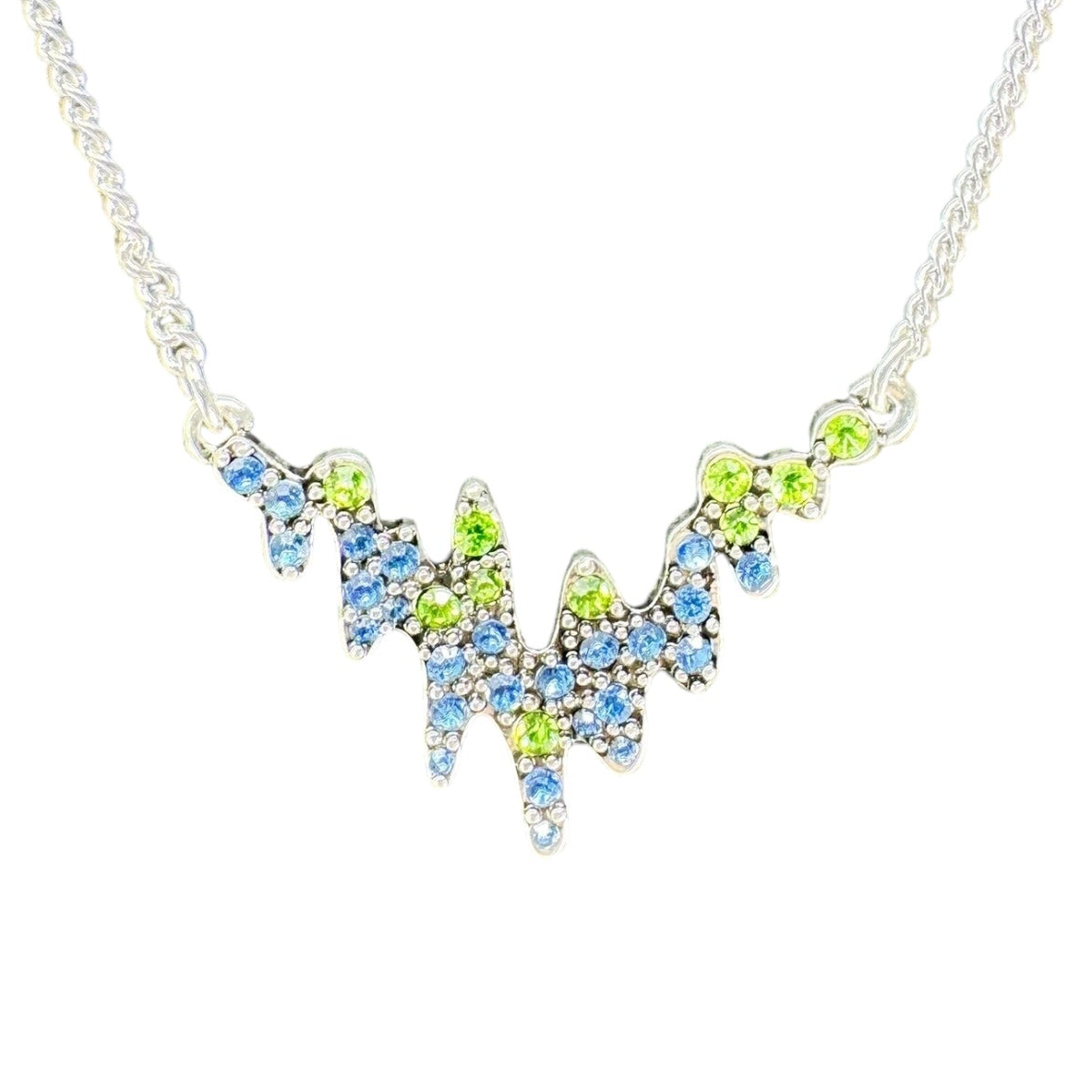 Inspired by Norwegian jewelry, the Necklace: Northern Lights A&C Oslo Norway features a silver chain and a jagged pendant adorned with blue and green crystals in a striking, wave-like pattern.