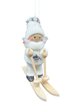 Handmade Figurine: Scandinavian Girl on Skis with White Snow Suit, featuring a girl in a white knitted hat and outfit, holding ski poles, standing on wooden skis, and includes a string for hanging.
