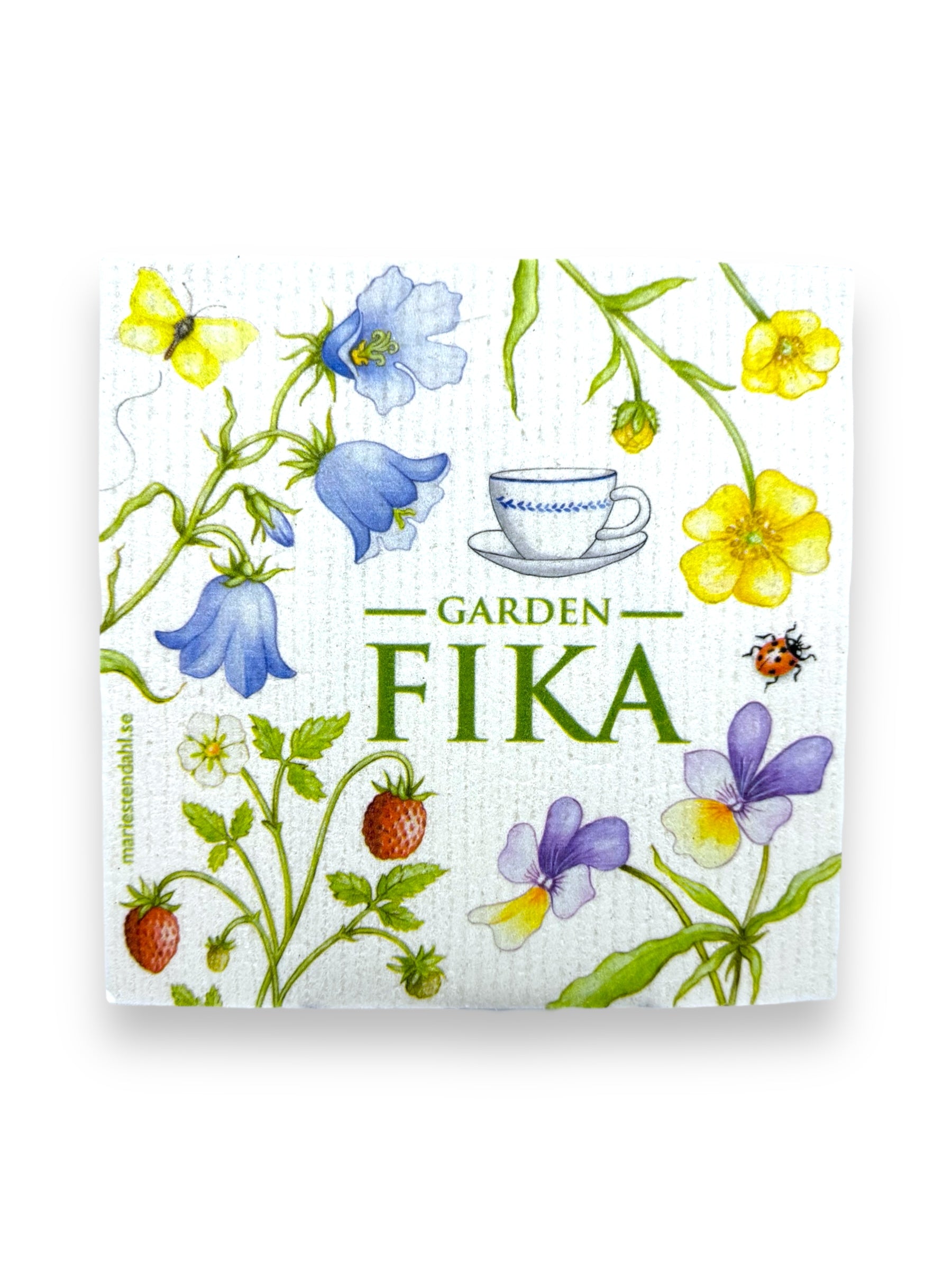 The Dish Cloth: Garden Fika by Marie Stendahl showcases a floral theme with blue and yellow flowers, strawberries, a teacup, and a ladybug. These super absorbent and environmentally friendly towels add charm and functionality to your kitchen.