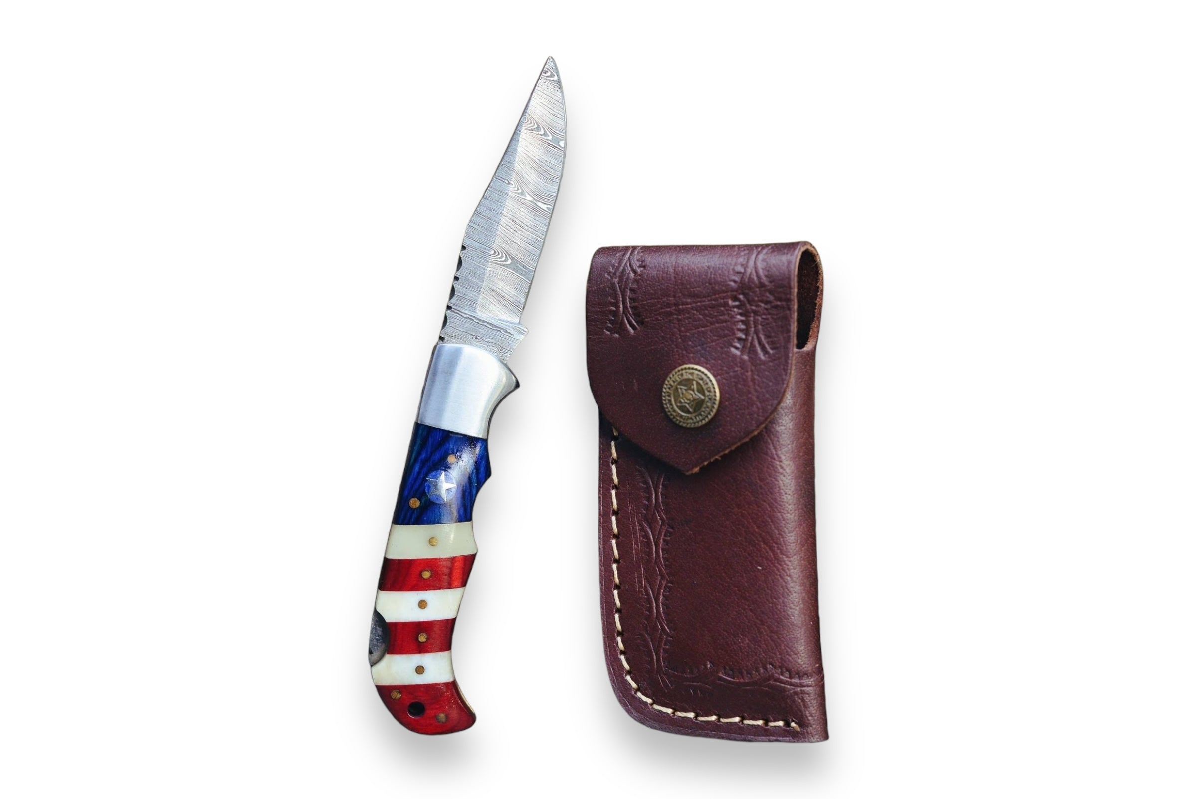 A bespoke USA Flag Damascus folding pocket knife, featuring a red, white, and blue handle, is displayed next to a brown leather sheath against a white background—ideal for anyone looking to purchase personalized gifts.