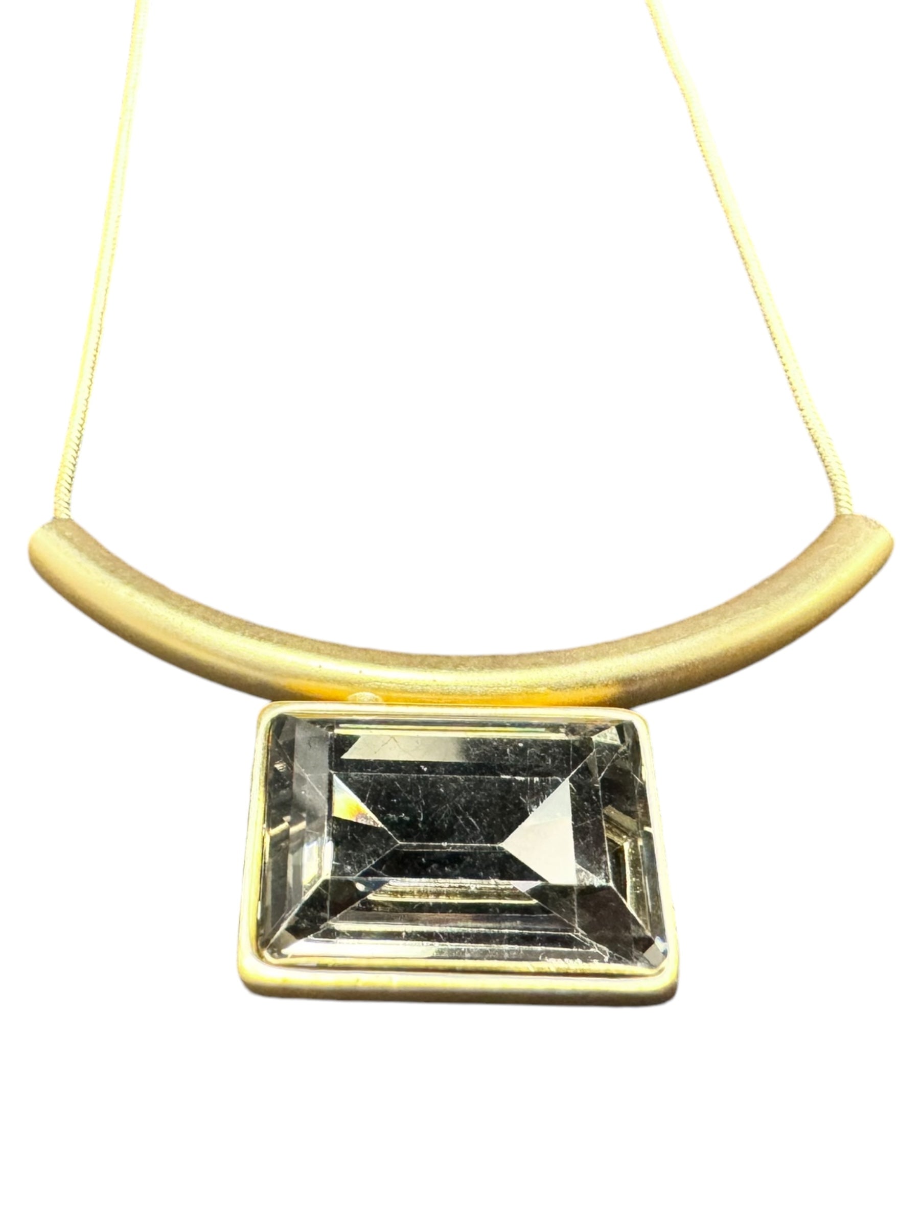 The Audrey Black Diamond Gold Plated necklace is crafted from high-quality brass and showcases a rectangular crystal pendant set in gold-tone metal, complemented by a curved bar above on a chain. Its minimalist Nordic design makes it versatile jewelry, perfect for any occasion.