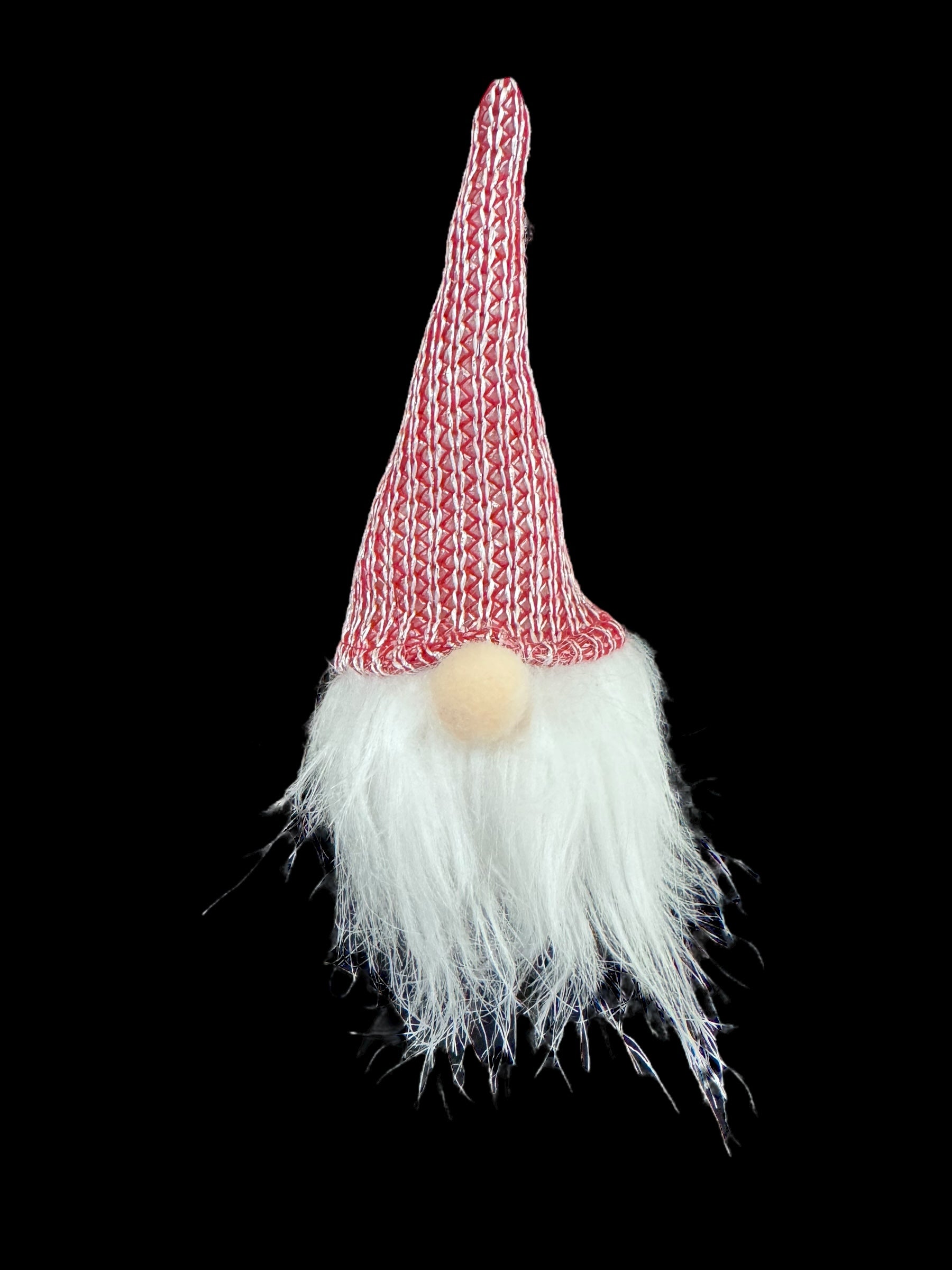 Discover the enchanting Ornament: Light Up Tomte Gnome, showcasing a tall red and white knit hat, round nose, and an impressive long white beard set against a black background. This delightful figurine is battery operated with A76 (LR44) batteries included for your convenience.