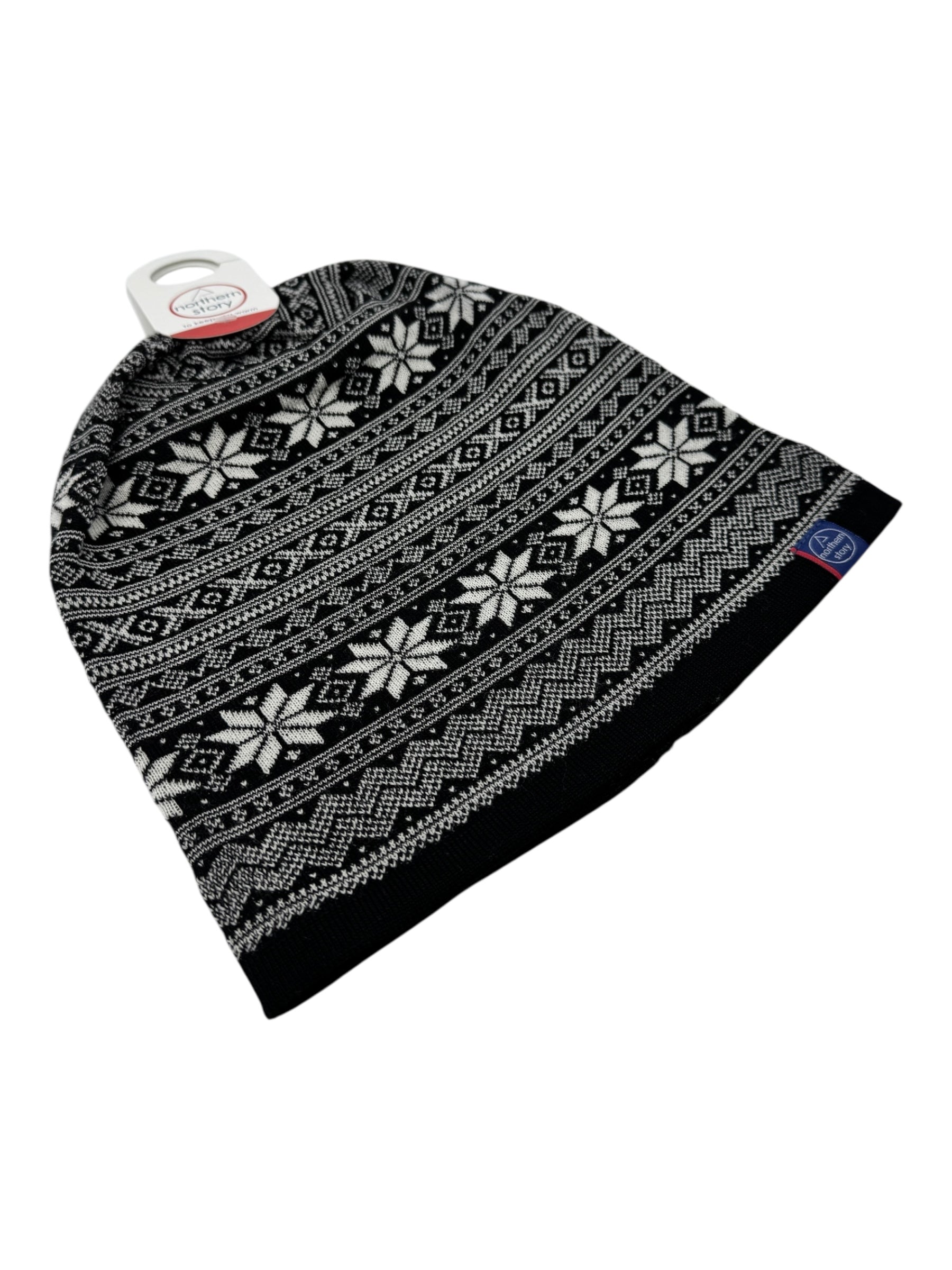 The Northern Story Setesdal Hat is a black knit hat made from 100% merino wool, featuring a Norwegian Selbu star and geometric pattern, shown with its tag attached.