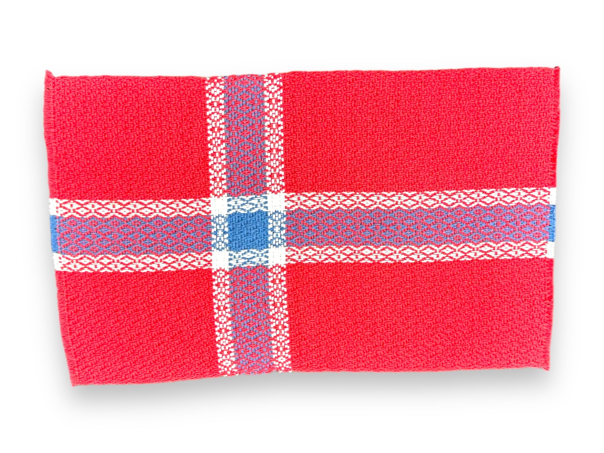 The "Placemat: Norwegian Flag" is a handcrafted red cloth piece made from 100% cotton, showcasing a woven pattern of white and blue intersecting stripes that replicate the classic plaid design inspired by the colors of the Norwegian flag.