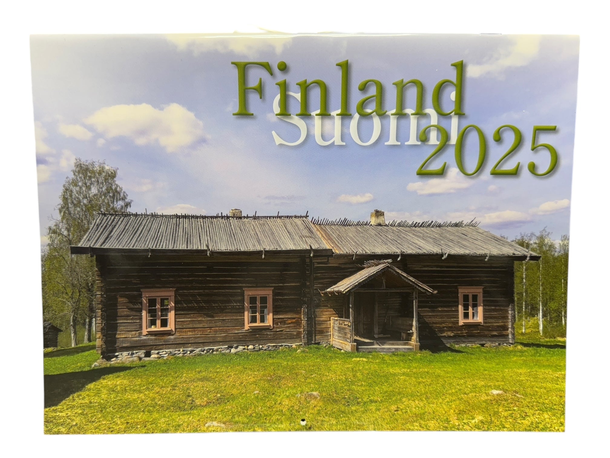 A rustic wooden house in a grassy field under a partly cloudy sky with the text Calendar: Nordiskal - Finland/Suomi 2025 - Bilingual Wall Calendar overlay.