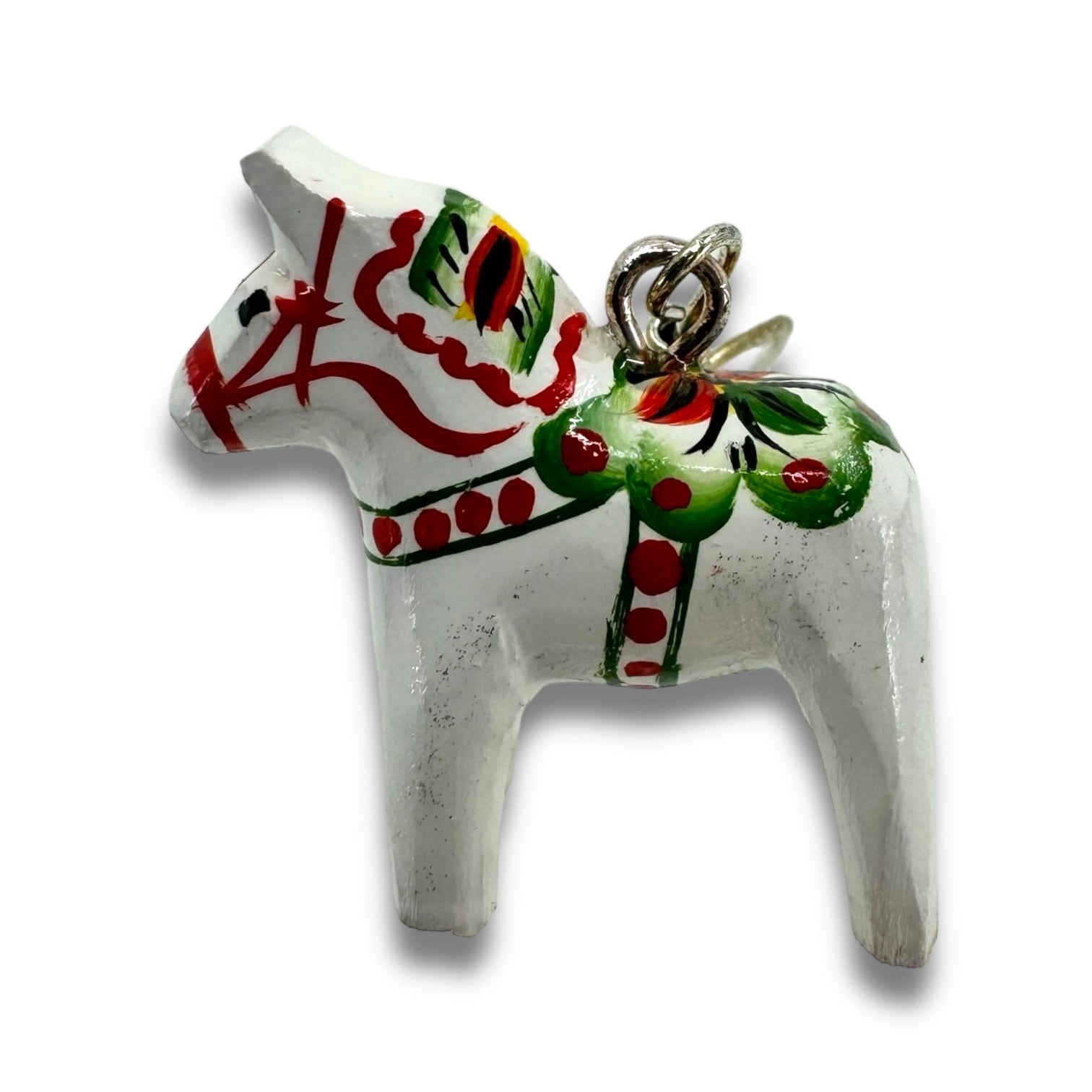 A pair of small hand-crafted white earrings designed in the shape of Dala horses, featuring colorful red and green painted details, is displayed against a plain background, capturing the charm of traditional Swedish art.