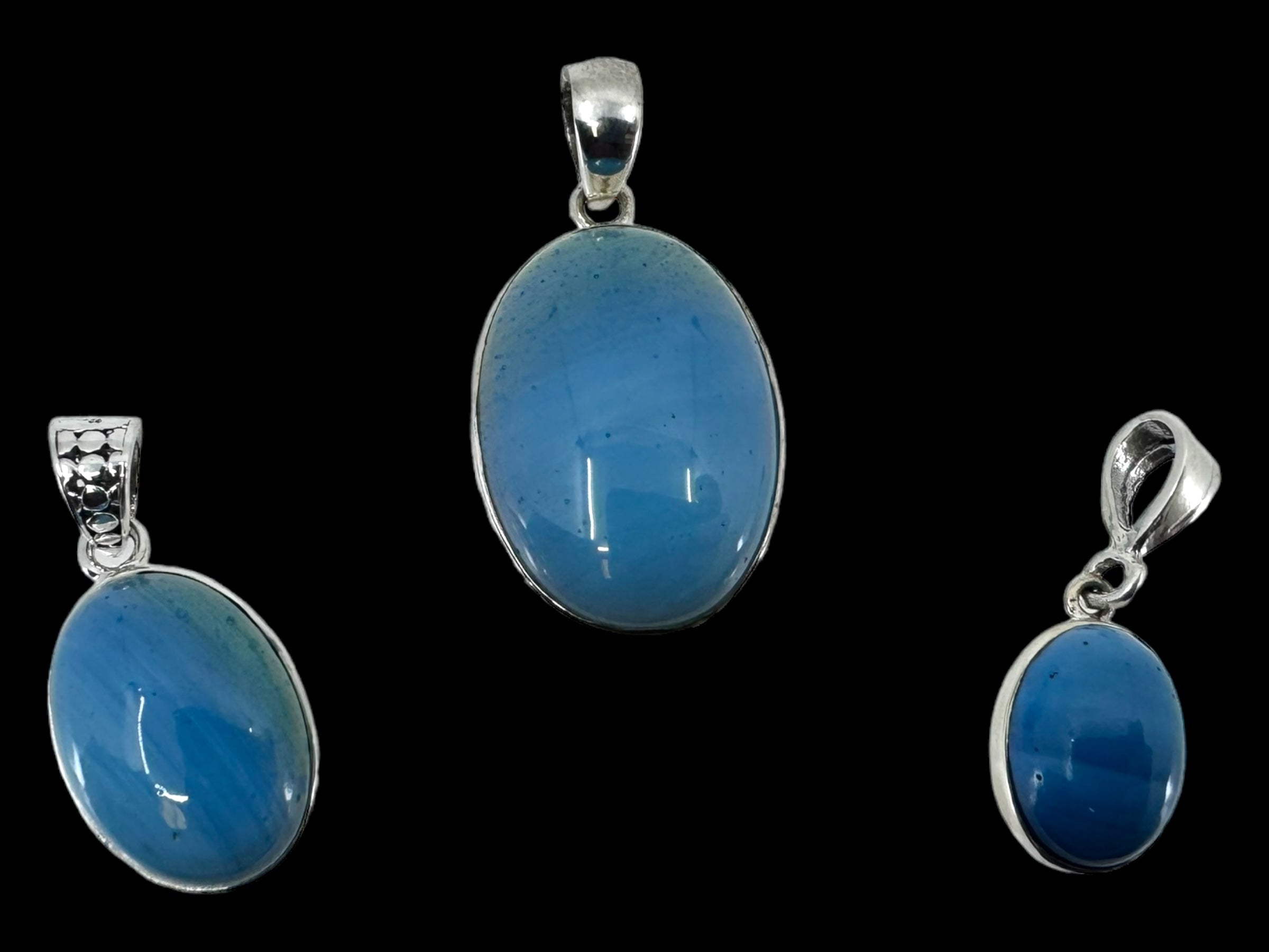 Three Plain Oval pendants in Swedish Blue, elegantly set in sterling silver, are showcased against a black background.