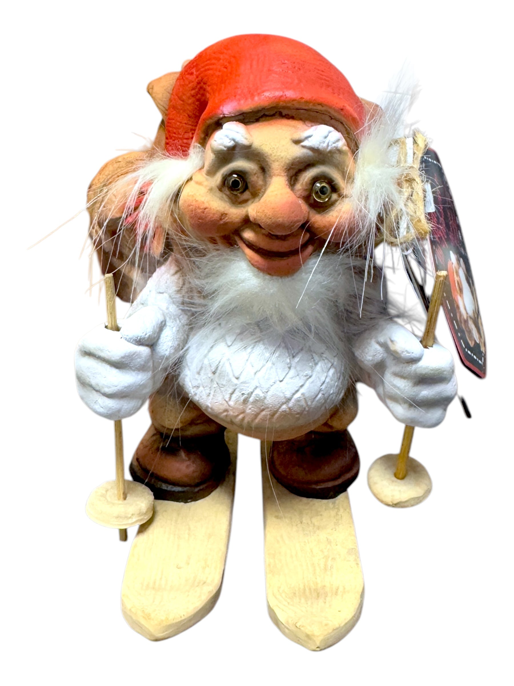 This Norwegian design figurine, named "Troll: NyForm - Nissen on Skis with Backpack," features a smiling gnome in a red hat holding ski poles while standing on wooden skis. It's a delightful addition to any collection, reminiscent of classic NyForm Troll craftsmanship.