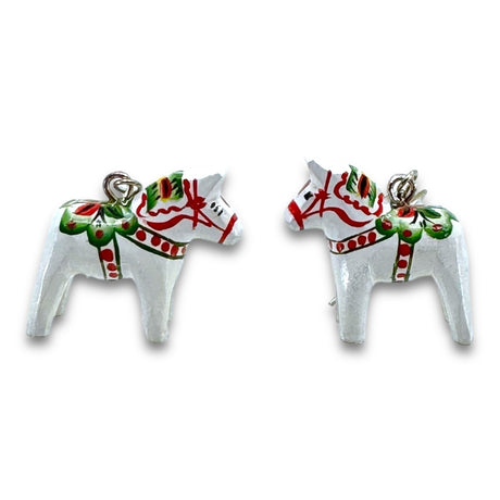 Two white Dala Earrings, inspired by traditional horse-shaped ornaments from Grannas Olsson, feature intricate green and red patterns.
