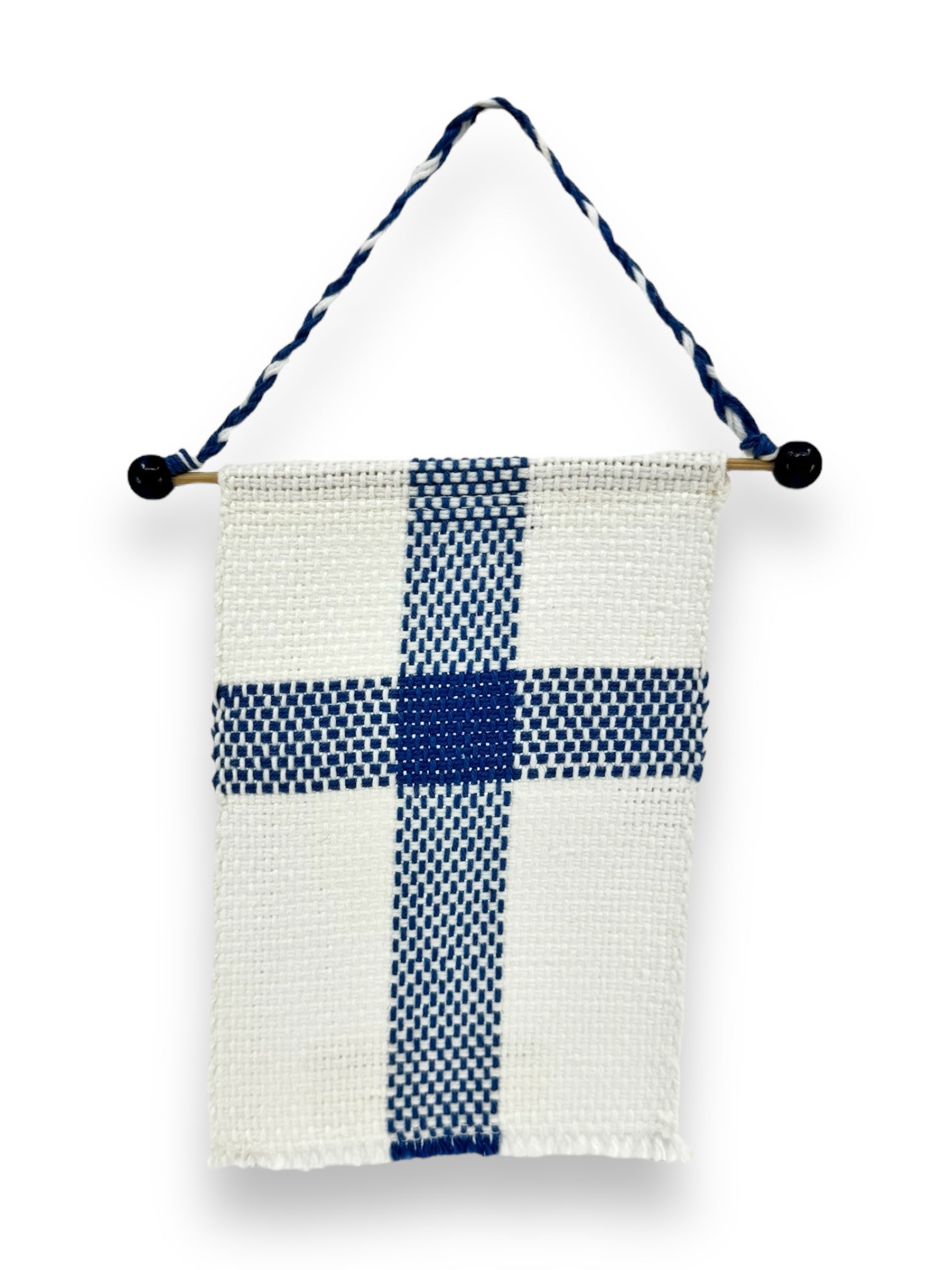 The Flag: Small Finnish Flag on Hanger (6.5"x4") is a hand-woven wall hanging made from 100% cotton, showcasing a blue cross on a white background reminiscent of the Finnish flag. It is stylishly hung by a twisted cord connected to a wooden dowel decorated with black beads.