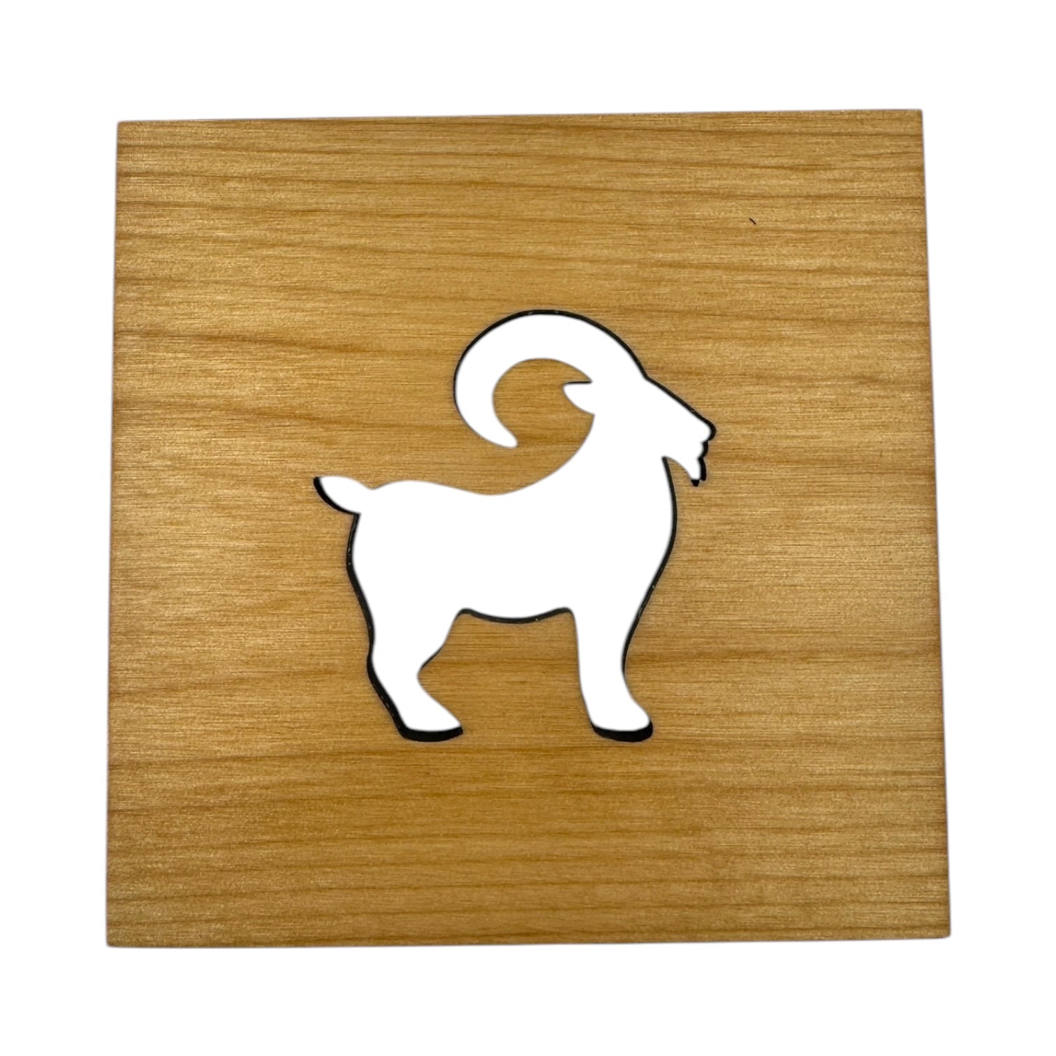 The Coaster: Swedish Goat 4x4 Square Alder Coaster features a white silhouette of a Swedish Goat with curved horns, inspired by Scandinavian tradition, on a wooden plaque.