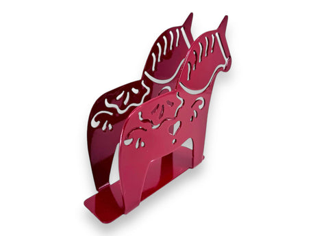 The Metal Swedish Dala Horse Napkin or Letter Holder is a red metal napkin holder with two stylized horses and kurbits-inspired cut-out patterns, bringing Scandinavian style to your table. Shown against a white background.