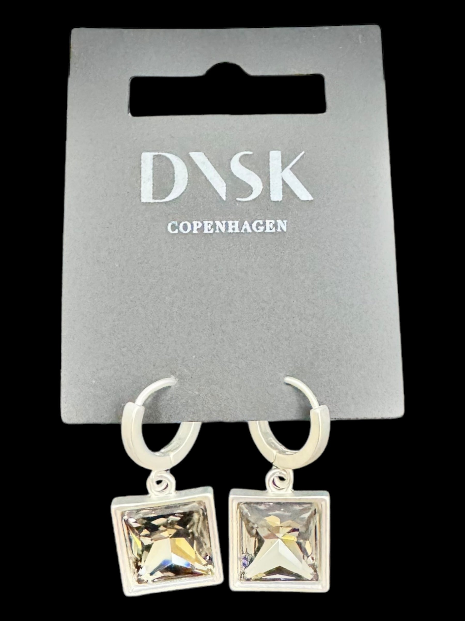 A pair of Audrey Black Diamond earrings in silver plated settings, showcasing a minimalistic Nordic design, displayed on a DVSK Copenhagen branded card.