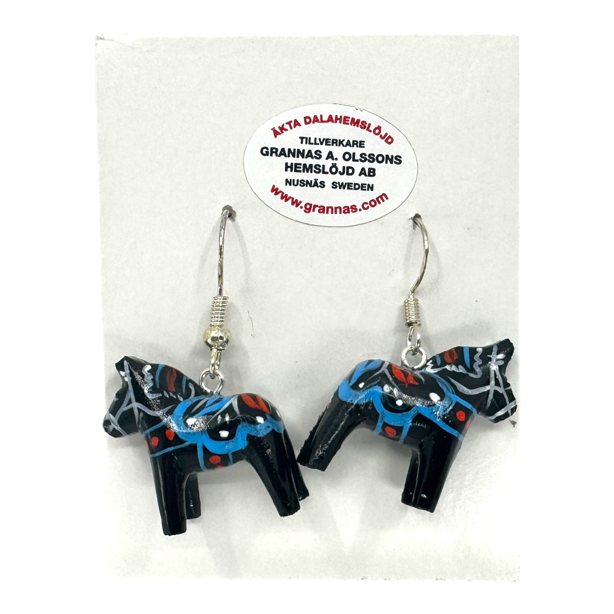 A pair of Dala Horse Black Earrings—handcrafted Swedish folk art (2cm/0.75 high) with blue, red, and white designs—displayed on a Grannas A. Olssons Hemslöjd AB branded card.