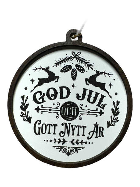 God Jul White & Gott Nytt År ornament features black holiday text with reindeer, pinecones, and foliage on white; hangs by a string—a festive way to celebrate Swedish Christmas traditions.