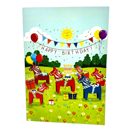 Card: Dala Horse Party, Birthday Card features red and blue Dala Horses celebrating with presents, balloons, a cake, and a Happy Birthday! banner in a sunny grassy field.