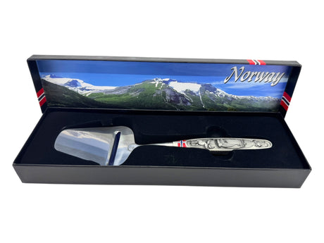 A smooth Norwegian cheese slicer with a pewter handle featuring Viking ship and moose images comes boxed, highlighting Nordic heritage.