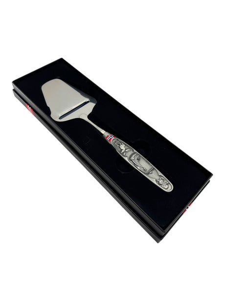 The Smooth Norwegian Cheese Slicer features a pewter handle with Viking ship and moose images, elegantly presented in a black box to highlight its timeless Nordic heritage.