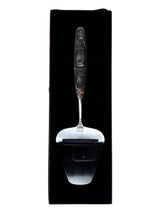 A smooth Norwegian cheese slicer with a pewter handle featuring images of a Viking ship and moose, reflecting Nordic heritage, beautifully presented in a black box.