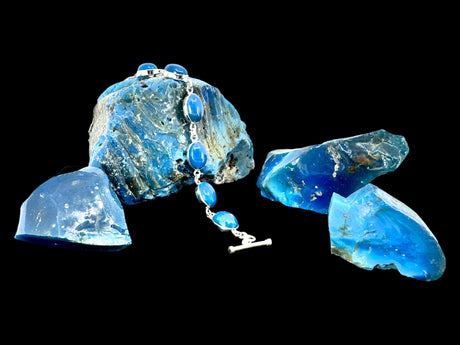 The elegant Plain Oval Seven Stone Swedish Blue Sterling Silver Bracelet features seven stunning gemstones arranged on a black backdrop.