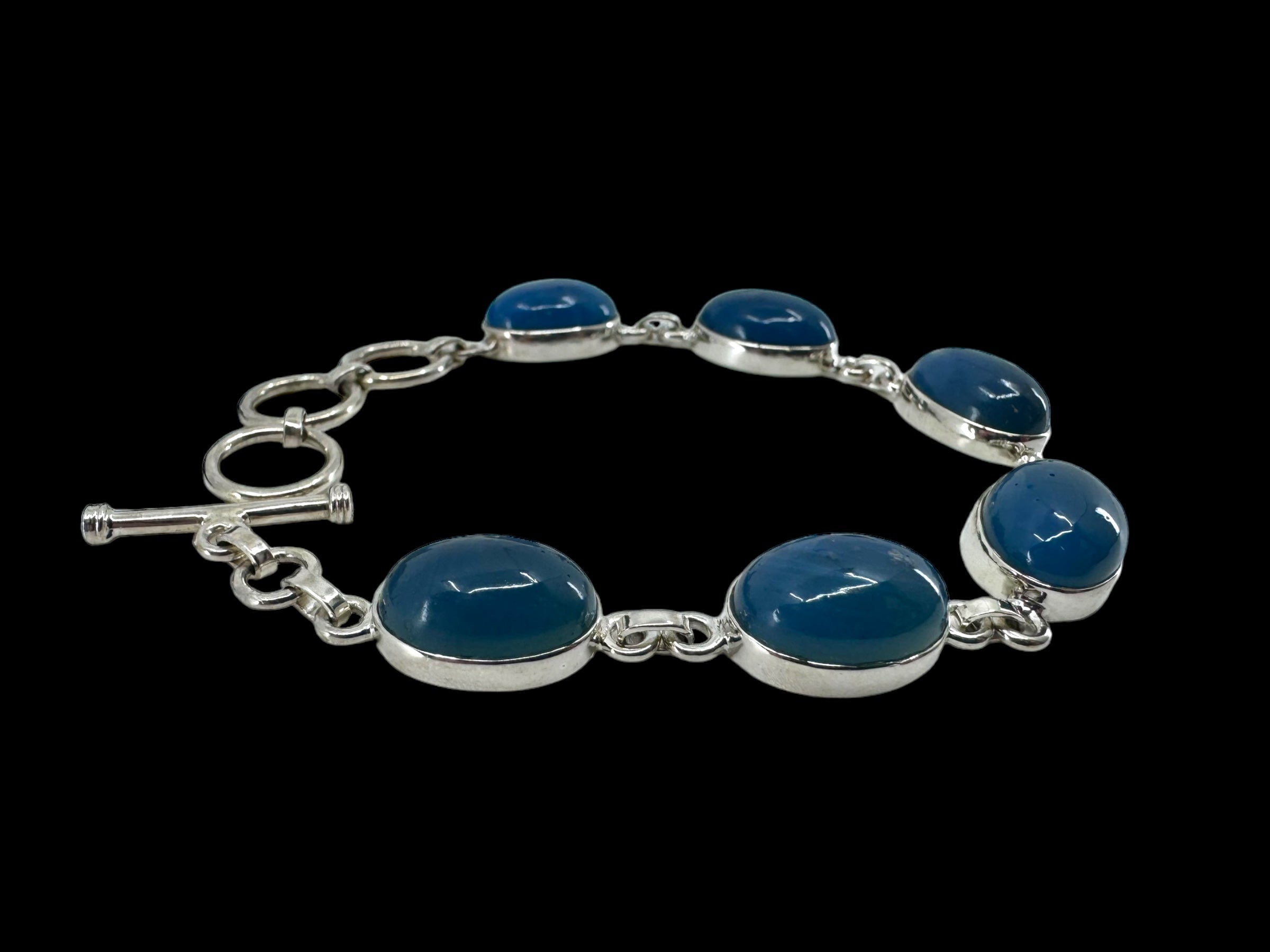 Bracelet: Plain Oval Seven Stone featuring seven oval blue stones set against a black background.