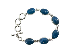A sterling silver bracelet with seven oval Swedish blue stones set in individual links on a chain is elegantly displayed against a black background.