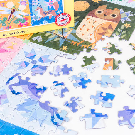 Partially completed PuzzleTwist: Quilted Critters 500-piece puzzle by Mirka Hokkanen, featuring an owl, with unassembled blue and white pieces scattered nearby.