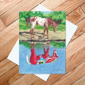 A vibrant image of a spotted horse, akin to a Dala Horse, stands by a pond with its colorful, abstract reflection reminiscent of Scandinavian design, similar to the artwork featured on the "Dala Horse Reflection" 5x7 card.