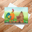 The "Dala Rooster Lord of His Domain" 5x7 card features an illustration of a rooster, hen, and seven chicks standing on grass against a wooden floor background, showcasing vibrant colors in the Swedish Dalahäst style.