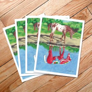 The "Dala Horse Reflection" card pack features four prints showcasing a horse gazing at its reflection in the water, painted red with lively patterns that evoke the Swedish Dalahäst and are imbued with Scandinavian style, all beautifully laid out on a wooden floor.