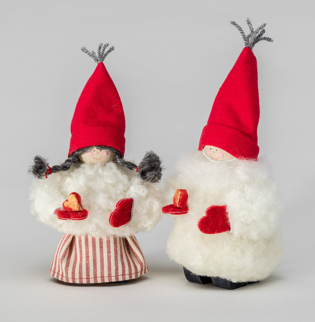 Two Santa Woman White Sheepskin and Red Heart figurines, with red hats and woolly sheepskin bodies, hold red hearts and stand on a flat surface against a plain background.