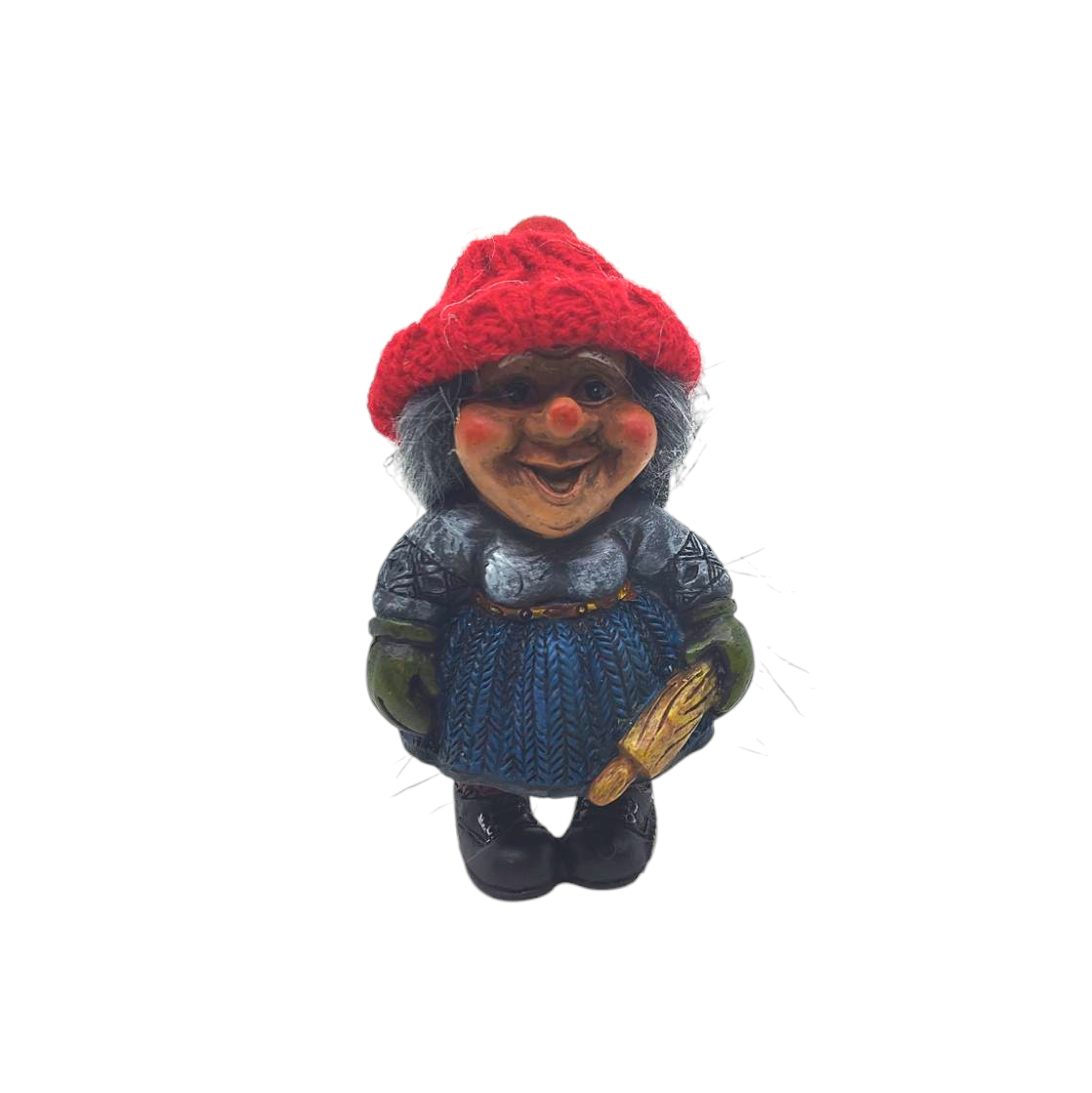 A ceramic Nisse wife figurine, donned in a red knit hat and blue dress, holding a rolling pin, stands on a white background—ideal for enhancing Scandinavian decor.