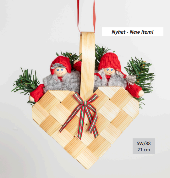 The Figurines: Santa Couple in a Woven Heart Basket showcases two plush dolls in red knit hats with fake green pine sprigs, a ribbon, and a tag that reads Nyhet - New item! and SW/88 21 cm, emphasizing its Swedish handcrafted origin.