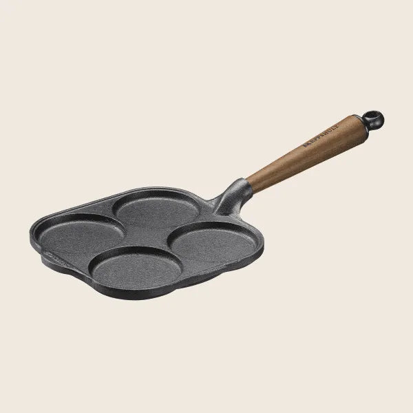 The Skeppshult Egg Pan, 8/20 cm, boasts a durable non-stick surface and walnut handle with five round cooking compartments, set against a neutral background.